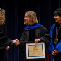 Laura Hawk shaking Provost Drake's hand, with President Mantella
